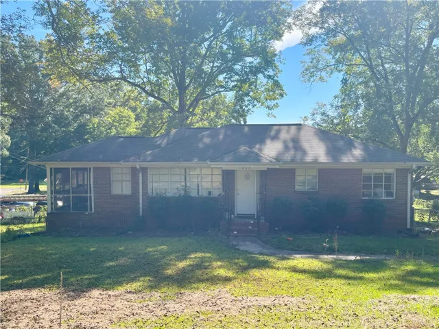 Mature trees shade a classic brick ranch home featuring a covered front entry.