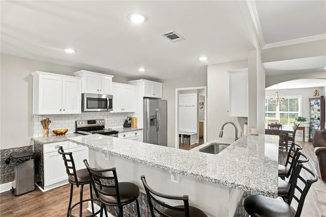 Polished granite countertops and classic white cabinetry define this open culinary space.