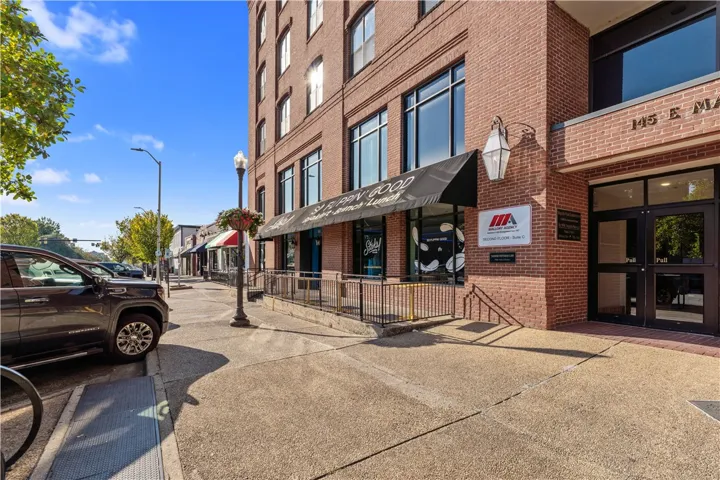 An impressive multi-story brick building stands prominently along a paved sidewalk.
