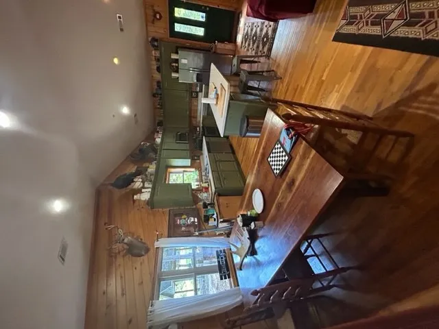 Warm wood paneling and hardwood floors frame a spacious open kitchen and dining area.