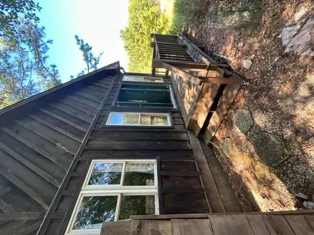 Rustic wood siding complements the elevated wooden deck set against a wooded backdrop.