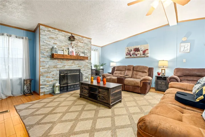 A stone fireplace anchors the living space, complemented by warm wood flooring.