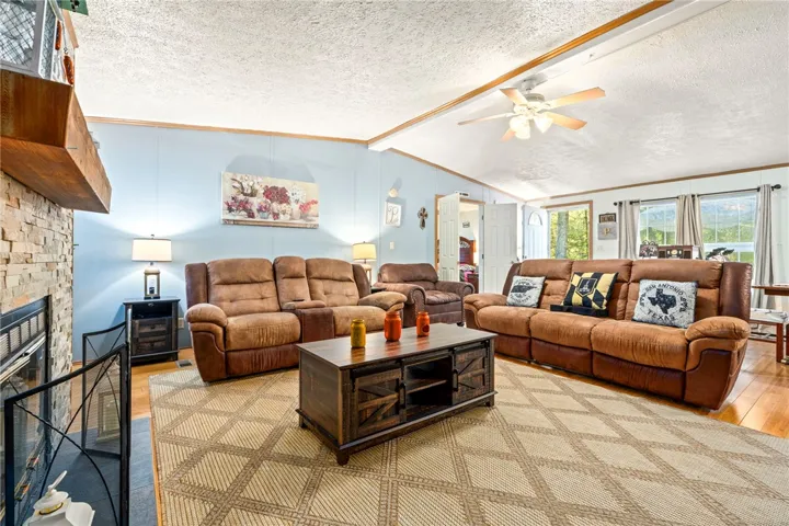 A stone fireplace adds warmth to this inviting living area featuring rich hardwood floors.