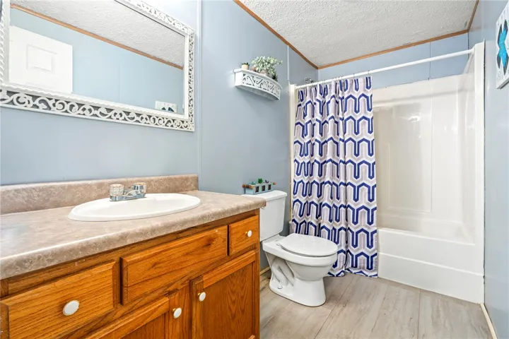 Functional bathroom layout features a wood vanity, laminate countertop, and classic tub and shower combination.
