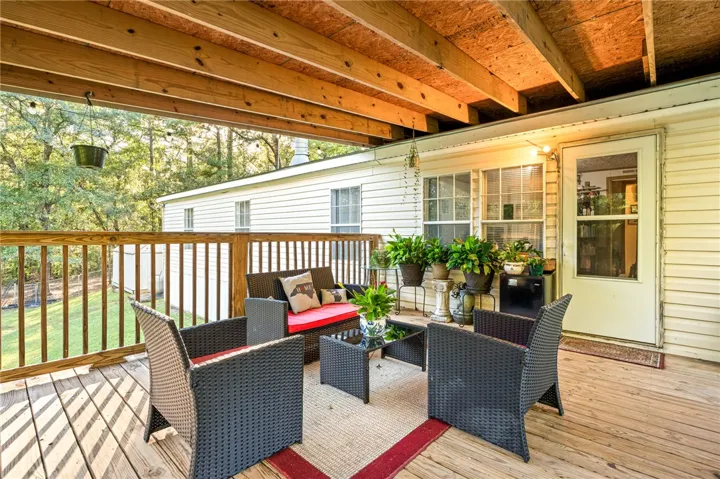A spacious covered deck features exposed wood rafters and offers views of the surrounding trees.