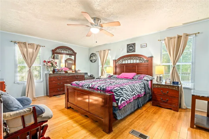 Warm wood flooring and multiple windows enhance this comfortable bedroom retreat.