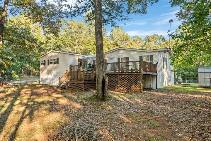 Mature trees frame a raised wooden deck system extending from the home's exterior.