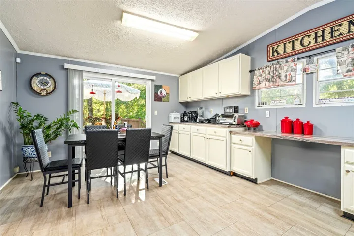 An open dining area flows into the kitchen under a smooth ceiling with tile floors.