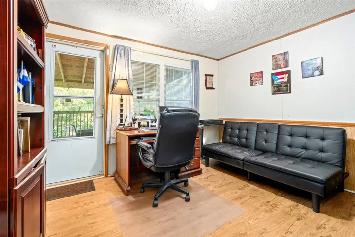 Warm wood flooring and an glass-panel door highlight this versatile home workspace.