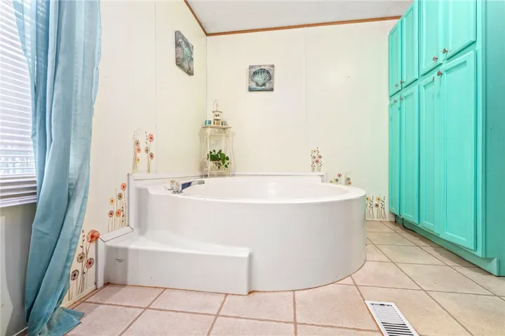 A spacious soaking tub highlights this bathroom with tiled flooring and built-in storage cabinets.