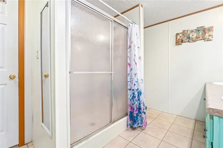 A functional bathroom highlights a walk-in shower enclosure alongside tiled flooring.