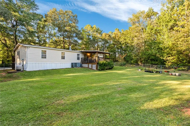 Mature trees frame a spacious, grassy lawn bordering the elevated wooden deck.