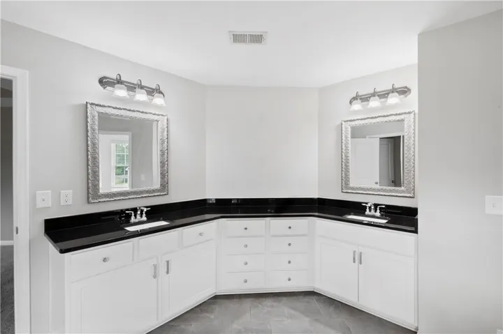 A spacious double vanity anchors this master bathroom alongside sleek tile flooring.