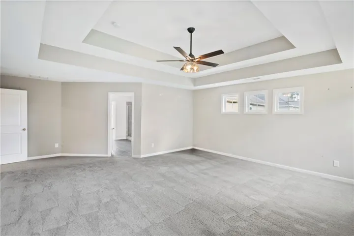 An elegant tray ceiling and soft wall tones define this comfortable, carpeted main suite.