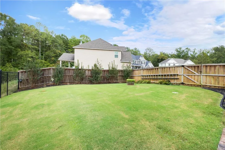 An expansive green lawn stretches across this fully enclosed private backyard.