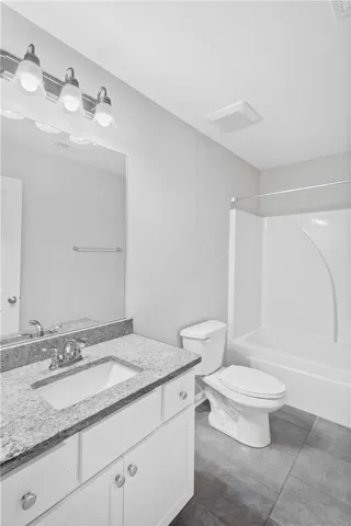 Polished stone counters and large-format tile flooring elevate this pristine bathroom space.
