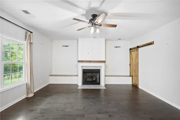 Rich hardwood flooring anchors the spacious living area anchored by a classic fireplace.
