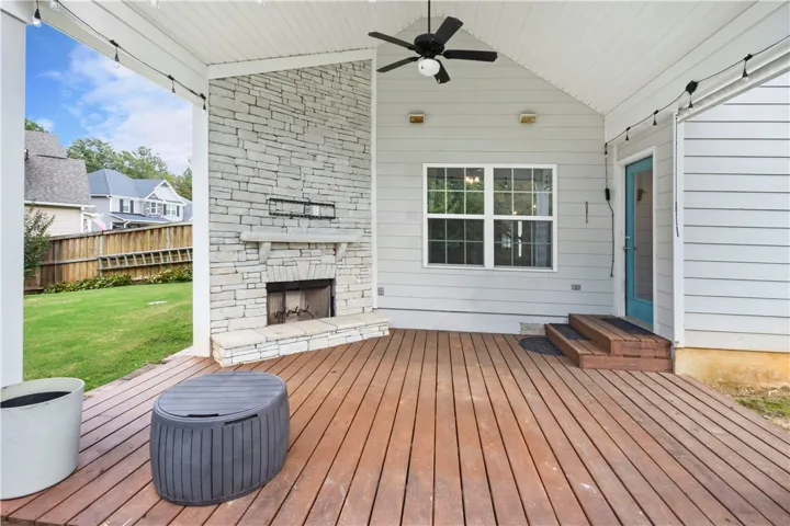 A spacious covered wood deck centers around a grand stone fireplace under a vaulted ceiling.