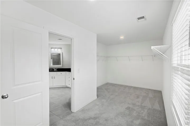 Ample wire shelving and soft carpeting define this functional walk-in closet space.