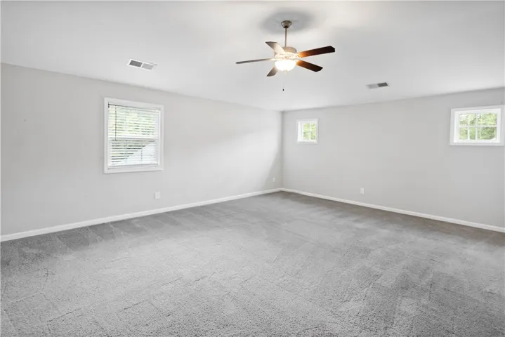 Plush wall-to-wall carpeting and multiple windows create a comfortable and airy atmosphere.