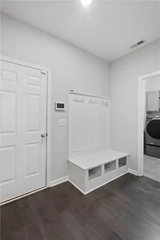Dark wood flooring contrasts beautifully with crisp white walls and a built-in drop zone bench.