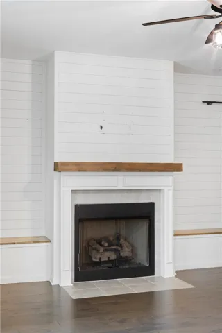 A classic fireplace with a rustic wood mantel serves as a focal point against shiplap walls.