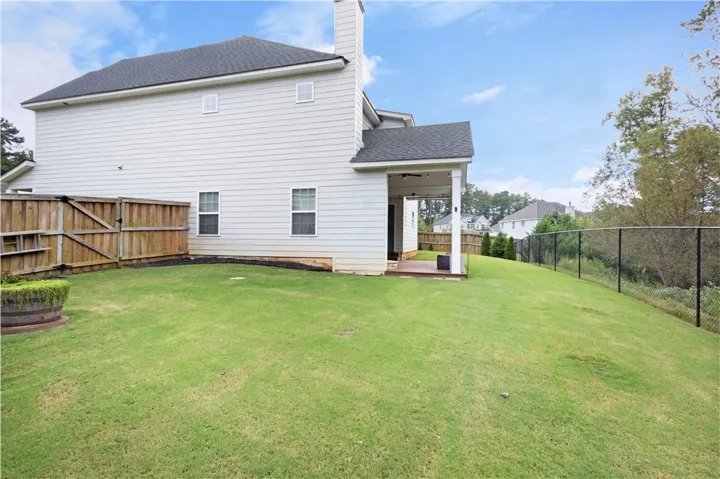A spacious grassy lawn stretches alongside this vinyl-sided home with a covered back porch.