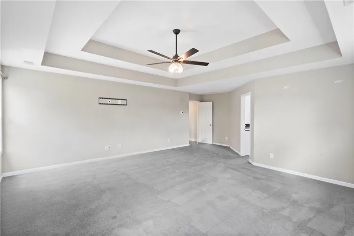 Plush carpeting anchors this spacious room beneath a classic tray ceiling.