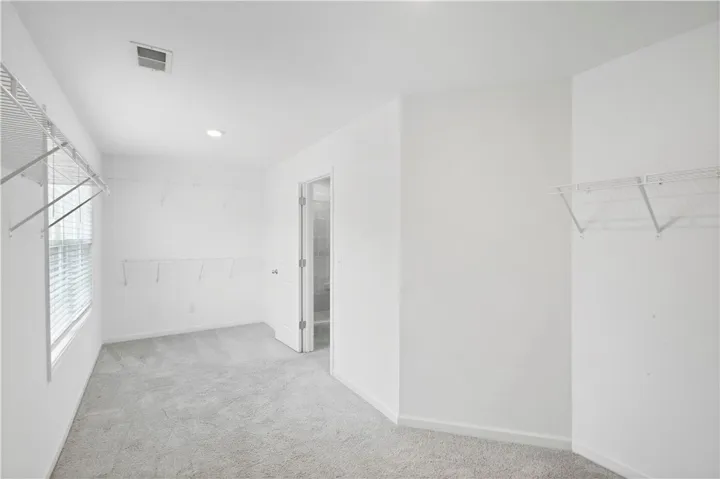 An abundance of wire shelving and soft carpeting define this spacious walk-in closet.