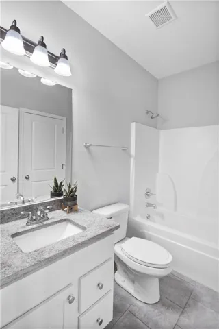 Modern stone countertops and neutral tile flooring elevate this pristine full bathroom.