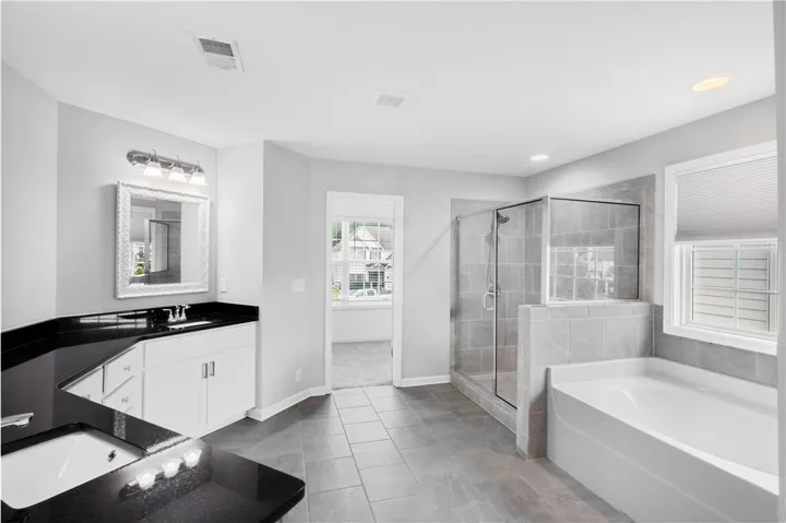 Polished tile flooring anchors a spacious layout featuring a glass shower and soaking tub.