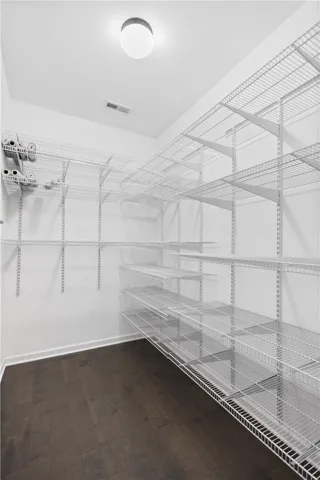 Ample wire shelving lines this functional storage space featuring rich dark wood flooring.