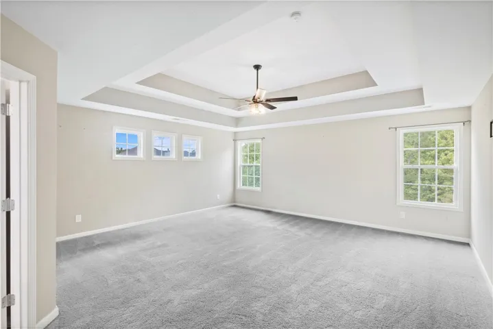 An elegant tray ceiling with extensive molding defines this generous bedroom featuring plush carpeting.