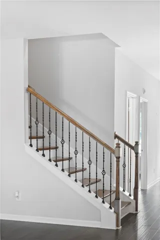 An elegant wooden staircase showcases intricate wrought-iron balusters and polished hardwood flooring below.