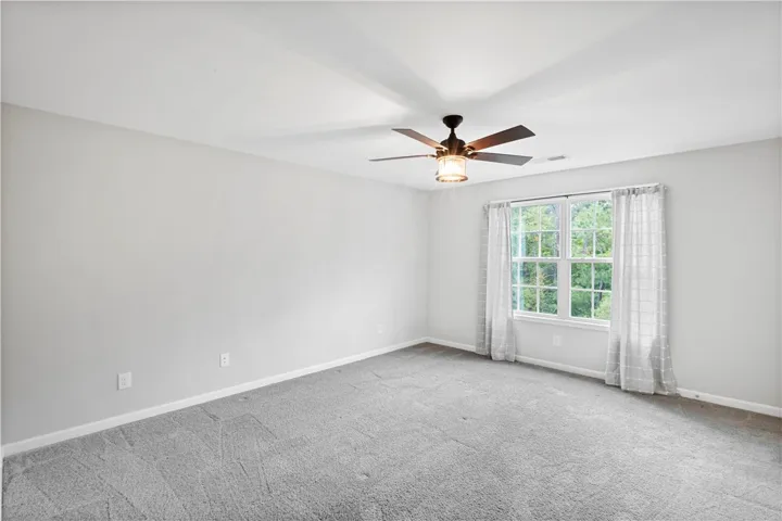 Plush carpeting and a multi-pane window framing backyard views anchor this spacious bedroom.