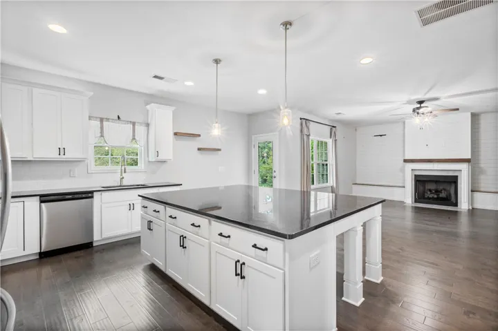 An open floorplan seamlessly connects the stone-counter kitchen to a fireplace-centered living area.