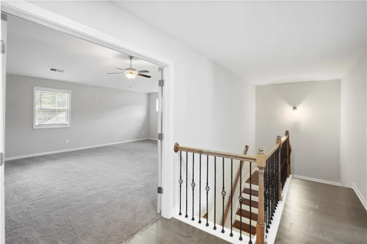Plush carpeting meets polished wood flooring along a detailed staircase railing on this level.
