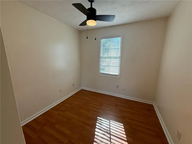 Rich wood flooring anchors this versatile space illuminated by natural light from a central window.