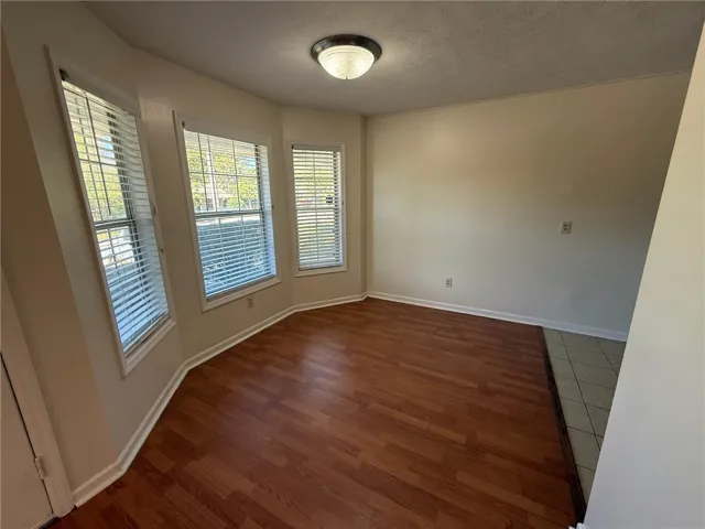 A bay window alcove illuminates this versatile space featuring rich wood-look flooring.