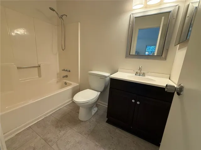 A classic tub shower combination sits adjacent to a dark wood vanity with solid surfacing.