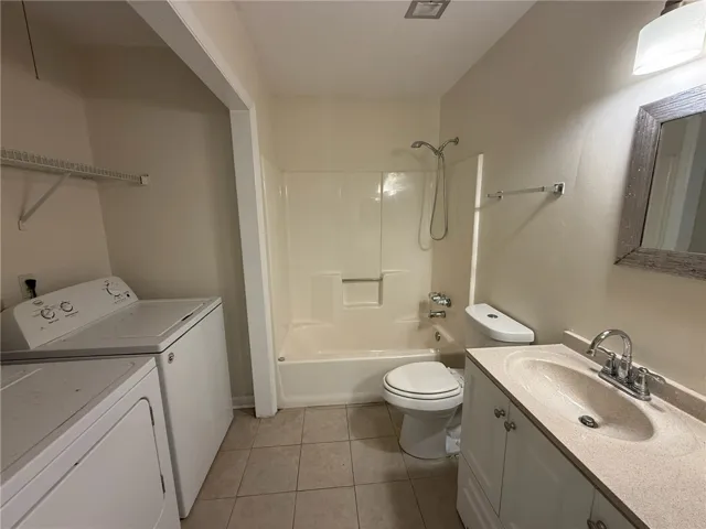 A functional layout integrates laundry appliances and bathroom fixtures over tiled flooring.