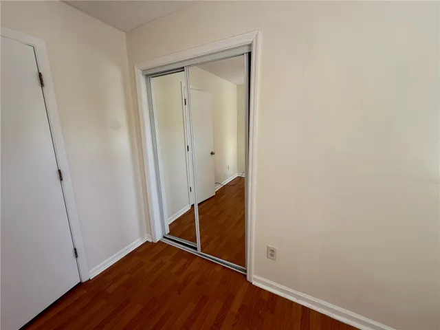 Rich wood flooring pairs with mirrored closet doors to enhance this functional bedroom space.