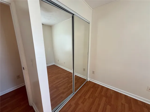 Warm wood flooring and sliding mirrored doors characterize this compact, light-filled bedroom layout.