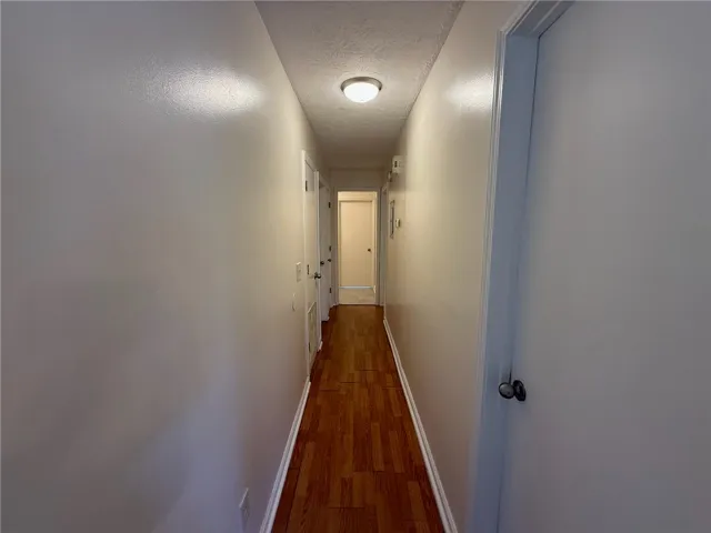 Rich wood flooring runs the length of this clean, well-lit hallway.