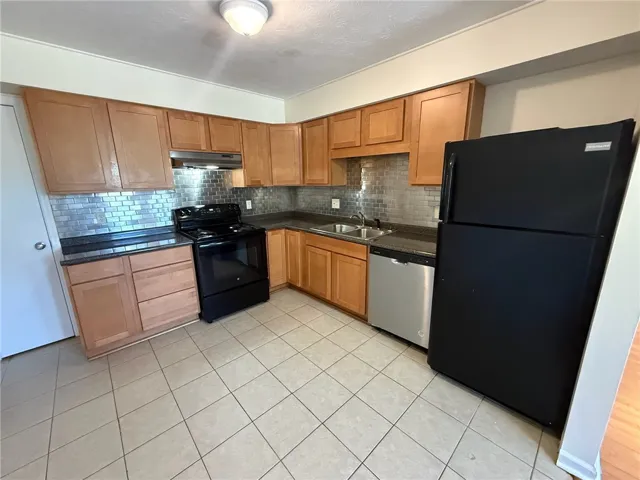 Gleaming tile flooring pairs beautifully with classic wood cabinetry and metallic backsplash tiling.