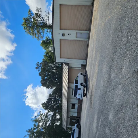 Ample parking surrounds this versatile detached outbuilding featuring metal siding and multiple roll-up doors.