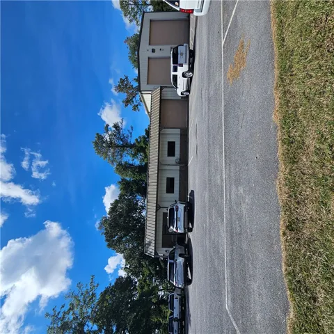 A spacious paved parking area sits adjacent to a multi-bay metal utility building.