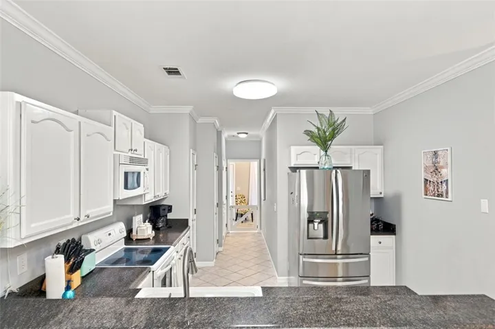 Granite countertops and clean white cabinetry anchor this functional, tile-floored culinary space.
