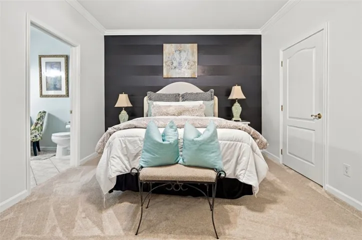 An inviting bedroom space features plush carpeting and elegant crown molding overhead.