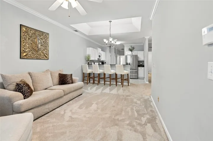 Plush carpeted flooring and elegant crown molding flow seamlessly into the adjacent kitchen.